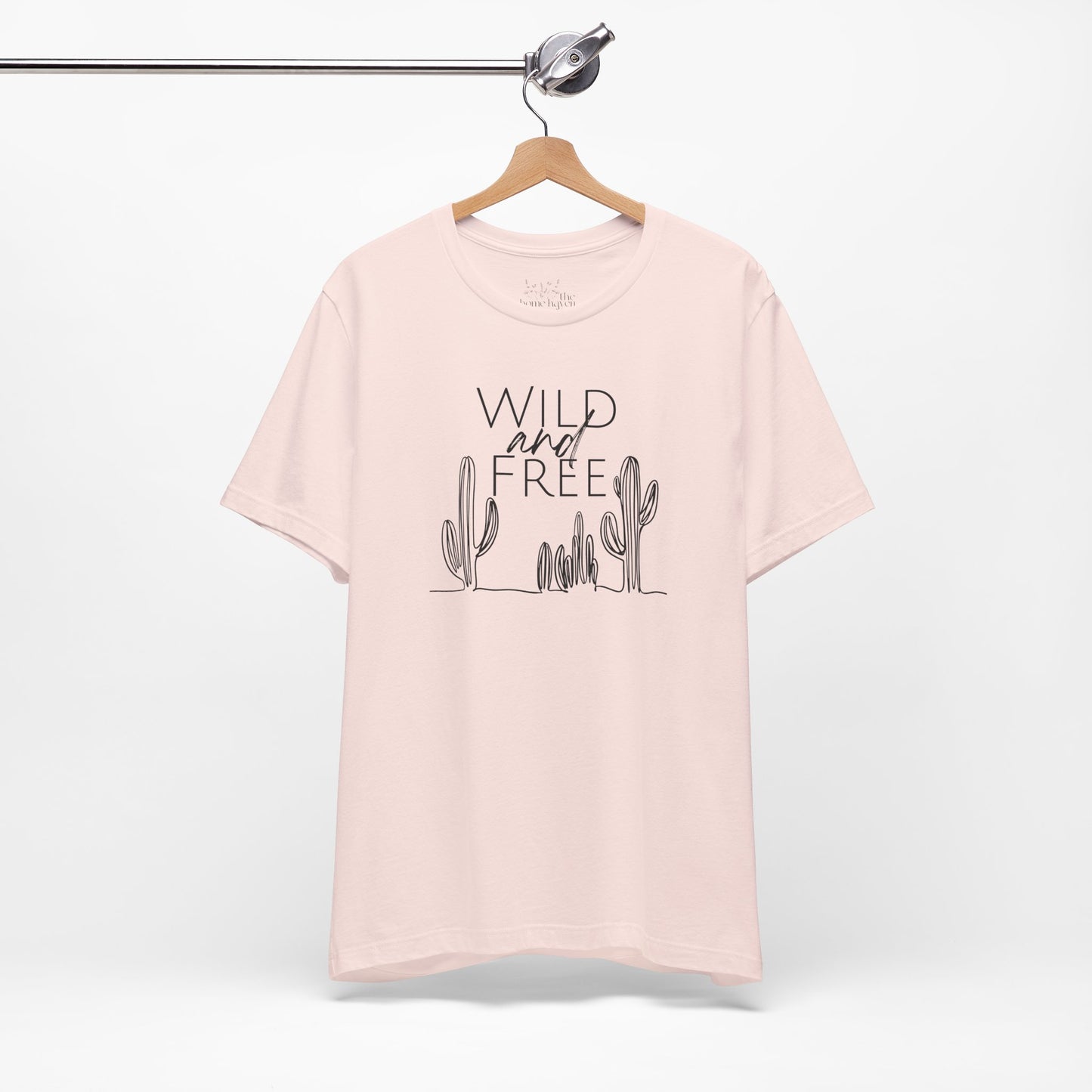 Light pink Wild and Free cactus graphic T-shirt on a hanger, offering a soft and stylish option for boho-inspired casual wear.
