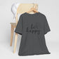Be Happy graphic t-shirt in charcoal gray with minimalist butterfly design displayed on a wooden chair with a white cap for a bold look.