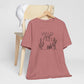 Rust-colored Wild and Free cactus graphic T-shirt draped over a chair, paired with a white cap for a casual and trendy vibe.