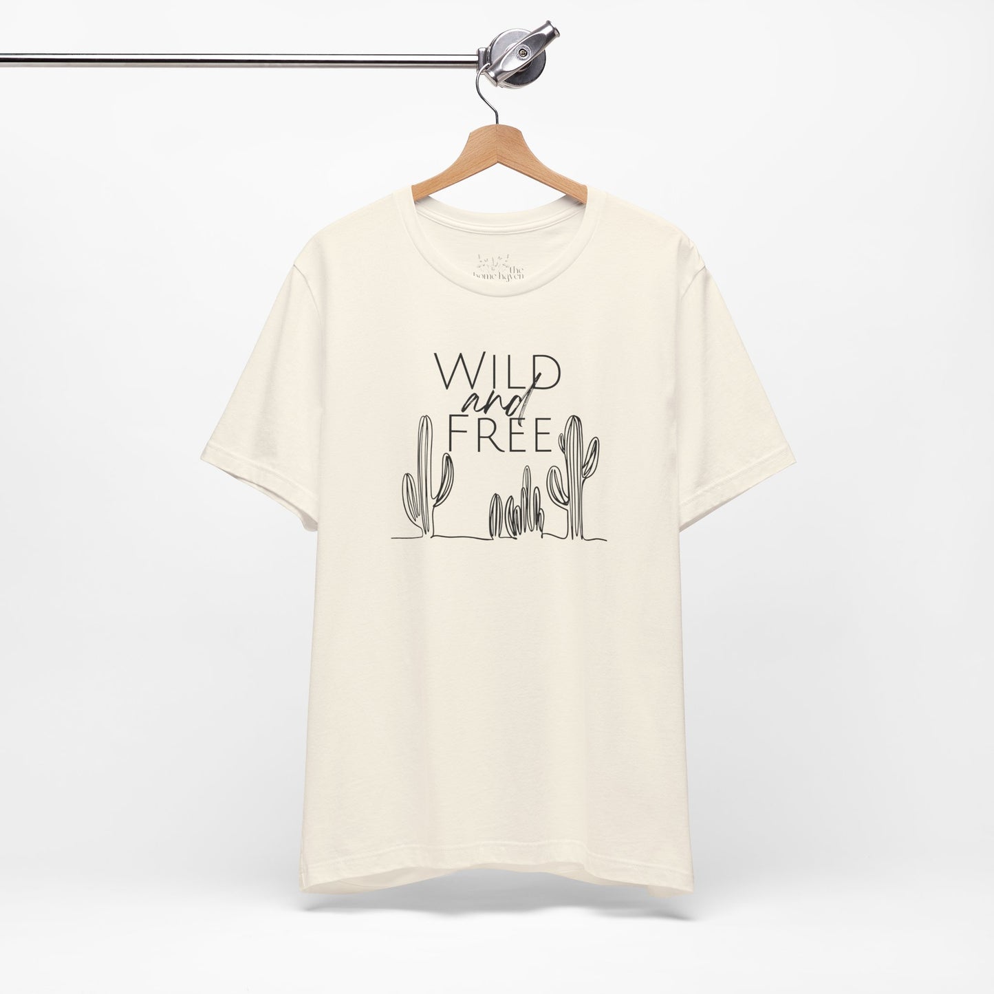 Cream Wild and Free cactus graphic T-shirt on a hanger, showcasing a minimalist desert-inspired design for casual and boho styles.