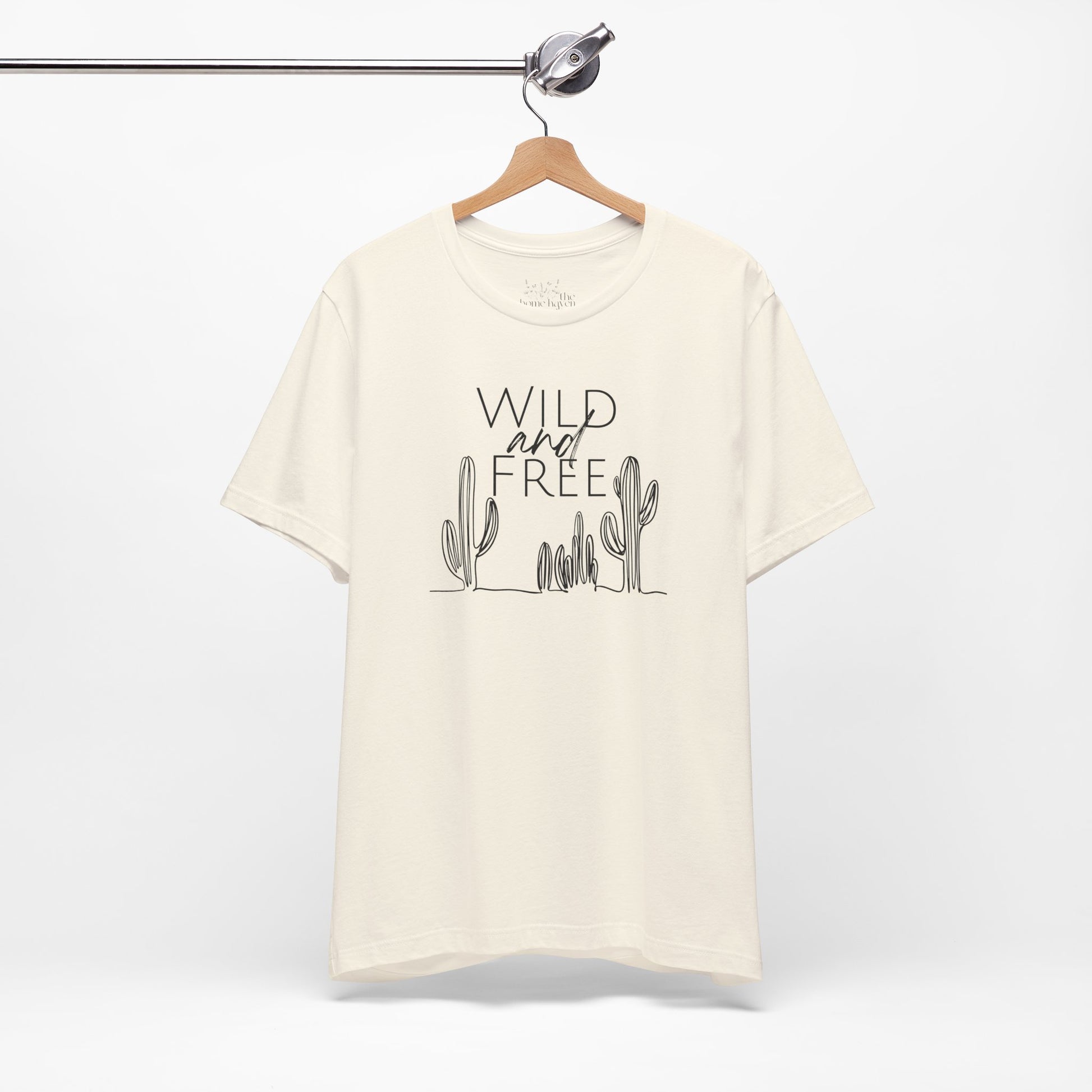 Cream Wild and Free cactus graphic T-shirt on a hanger, showcasing a minimalist desert-inspired design for casual and boho styles.