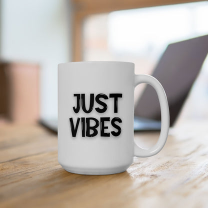 Large white ceramic mug with 'Just Vibes' text in black, set on a wooden desk near a laptop in a modern workspace.