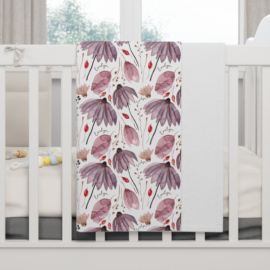 Personalized wildflower baby blanket draped over crib.