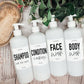 Set of 16oz white PET pump bottles labeled shampoo, condition & moisturize, face wash, and body wash. Stylish dispensers with floral and greenery accents.