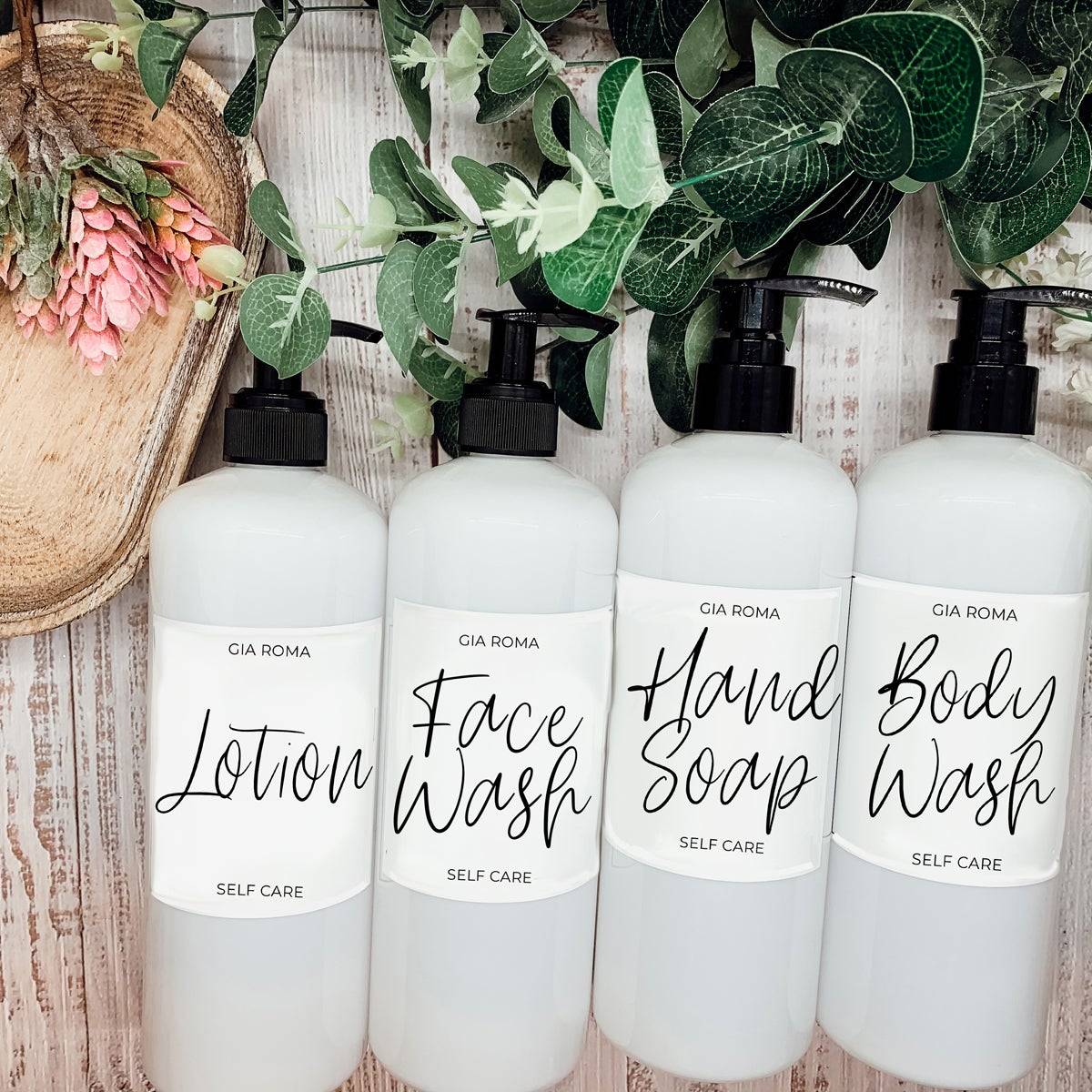 Set of 16oz white PET pump bottles labeled lotion, face wash, hand soap, and body wash. Stylish dispensers with greenery decor.