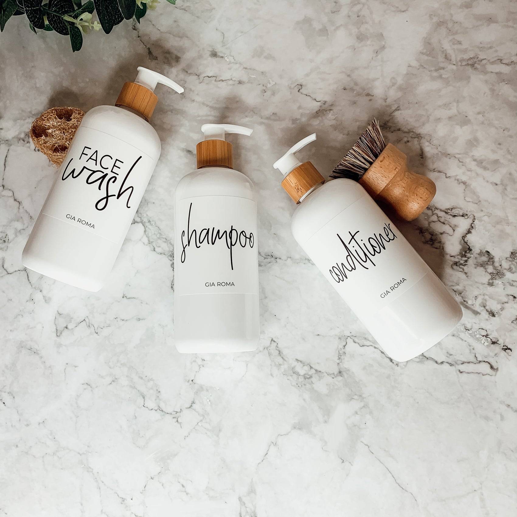 Three 16oz white PET pump bottles labeled face wash, shampoo, and conditioner. Stylish bathroom dispensers with bamboo pumps.