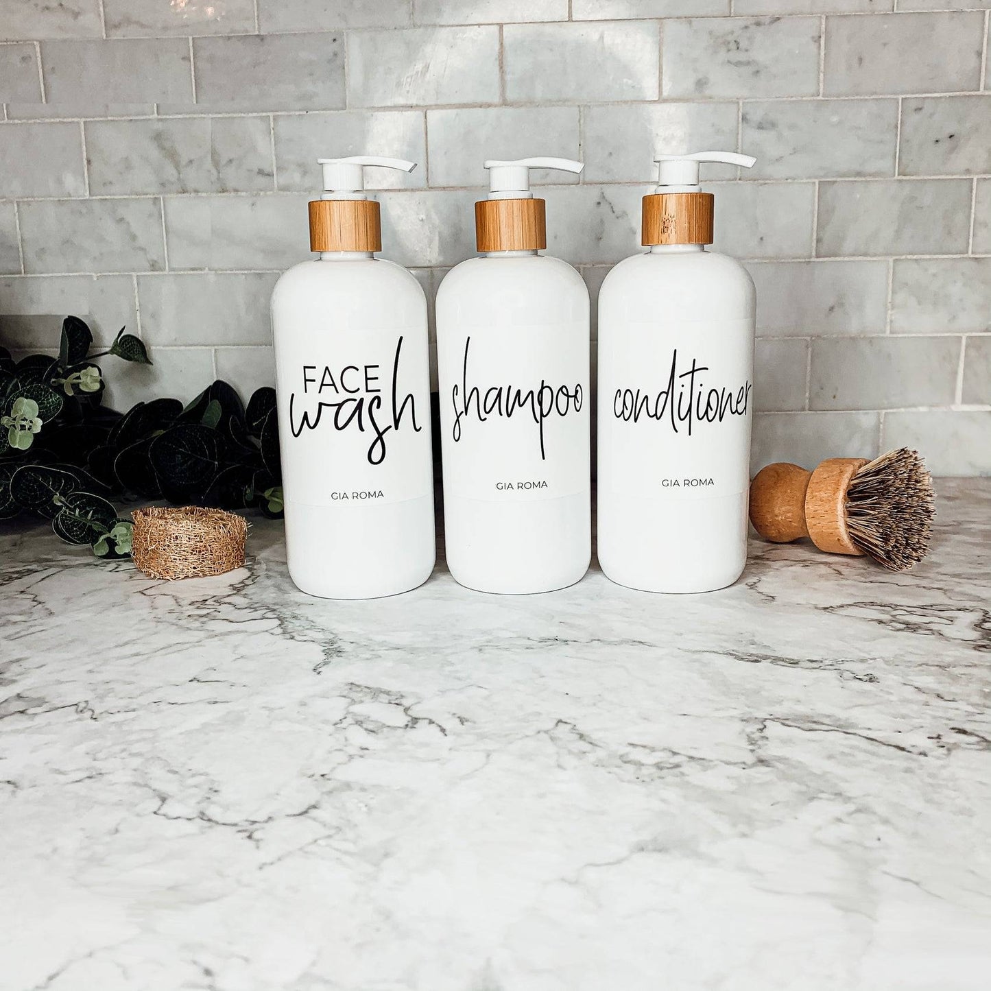 Three 16oz white PET pump bottles labeled face wash, shampoo, and conditioner with bamboo and white pumps. Elegant bathroom countertop dispensers.