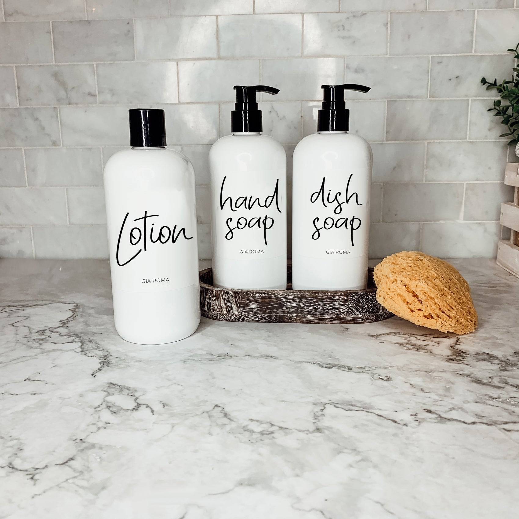 Three 16oz white PET pump bottles labeled lotion, hand soap, and dish soap. Reusable dispensers with a sponge on a marble countertop.