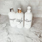 Three 16oz white PET bottles labeled shampoo, face wash, and conditioner with silver and gold flip tops. Minimalist bathroom dispensers.