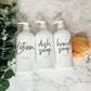 Three 16oz white PET pump bottles labeled lotion, dish soap, and hand soap. Reusable dispensers with a sponge and greenery on a marble countertop.