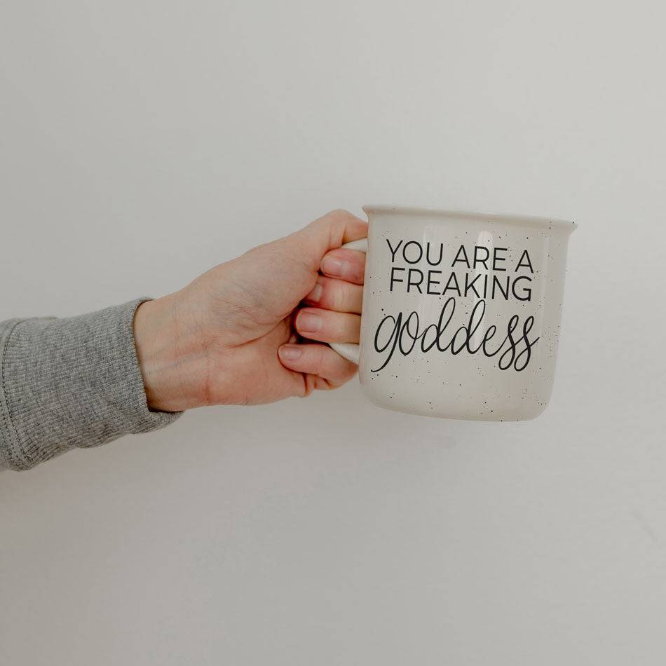 14.5oz ceramic coffee mug with 'You Are a Freaking Goddess' quote, held by a hand against a plain background.