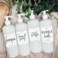 Set of 16oz white PET pump bottles labeled shampoo, hand soap, face wash, and bubble bath. Stylish dispensers with floral and greenery accents.