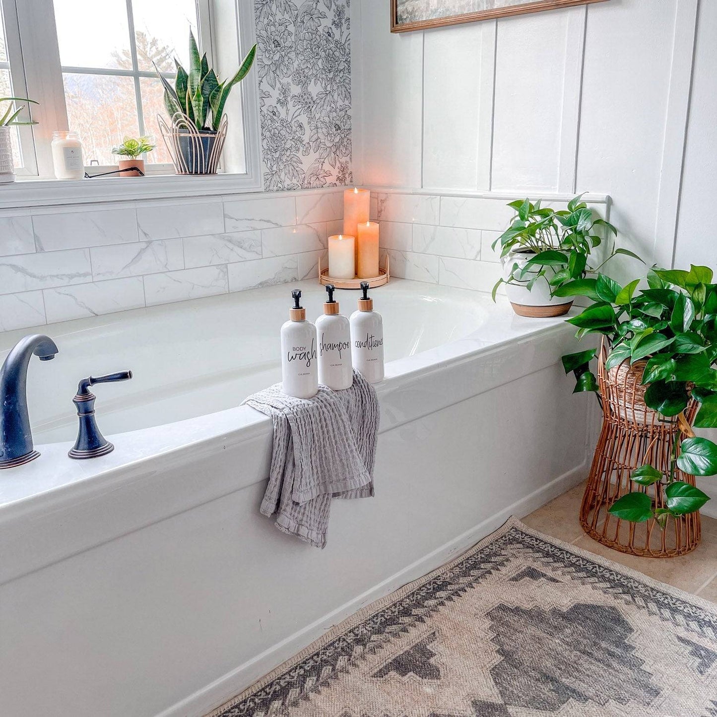 16oz white PET pump bottles labeled shampoo, conditioner, and body wash displayed on a bathtub ledge. Stylish bathroom decor with greenery.